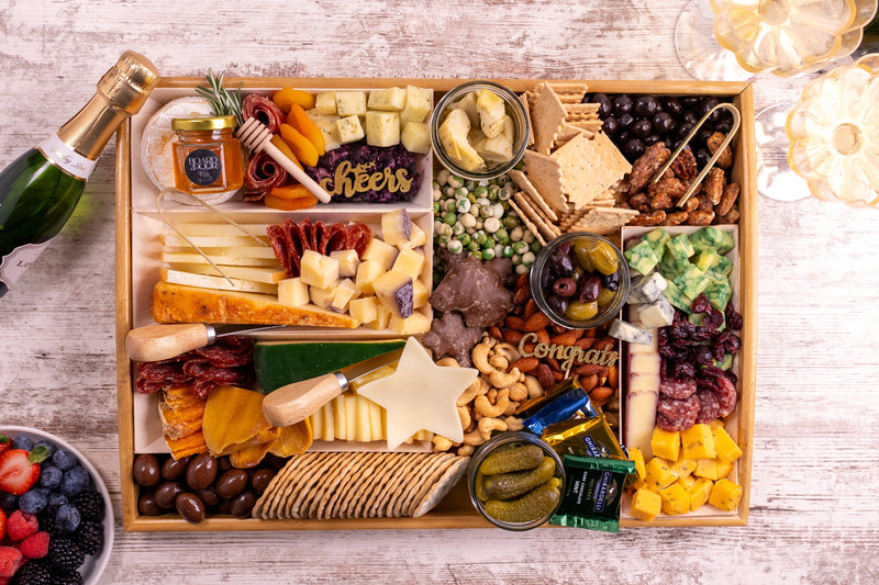 Assorted charcuterie board with cheeses, meats, and fruits on a wooden surface.