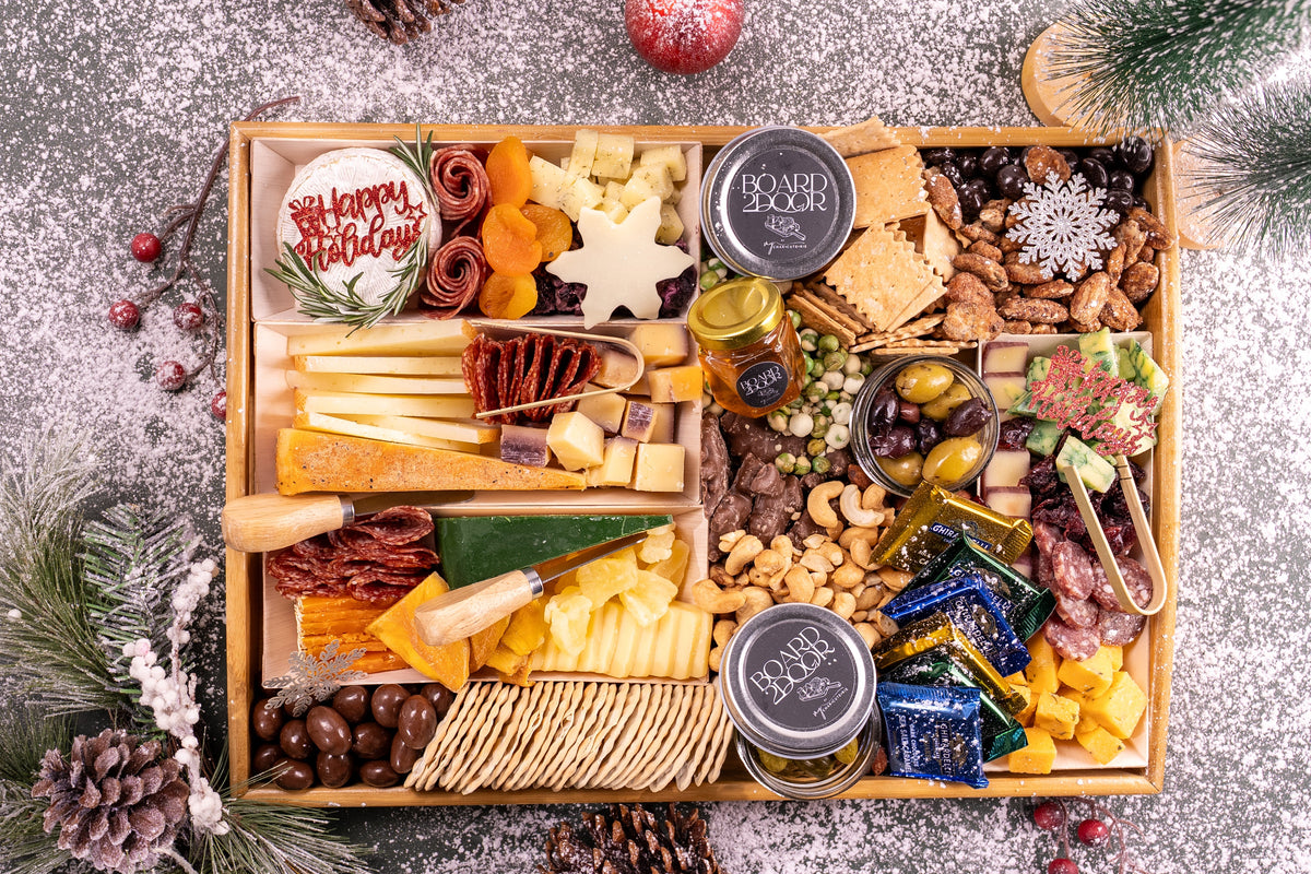 Gourmet charcuterie board with various foods and decorative elements on a textured surface.
