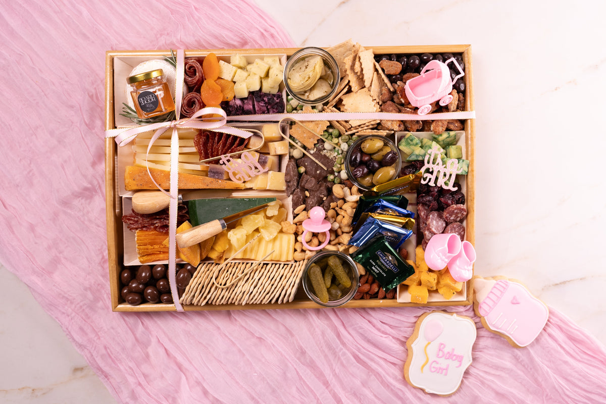 Gourmet food platter with various snacks on a pink surface
